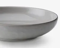 En rund, lav skål med en glat, mat lysegrå yderside og en blank lysegrå inderside. Skålen har en let hævet kant med en diskret, mørkere grå kant. Designet er minimalistisk og moderne med rene linjer og en blødt buet profil.