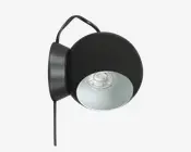 En moderne vægmonteret lampe med et mat sort, rundt metalhus. Lampen har en cirkulær, åben front med en hvid, reflekterende inderside, der forstærker lyset. Pæren er forsænket inde i lampen, og en synlig sort ledning går ud fra bunden. Designet er minimalistisk og moderne, velegnet til forskellige indretninger.