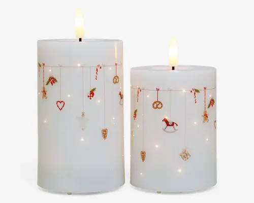To hvide bloklys med glat overflade, hver med et flammefrit LED-lys i toppen. Lysene er dekoreret med små, festlige julemotiver og ornamenter, såsom slikstokke, hjerter, kringler, kristtorn, gyngeheste og gaveæsker, der hænger fra tynde guldfarvede snore rundt om den øverste del af lysene. Små indbyggede LED-lys er spredt over overfladen og giver en varm, glødende effekt.