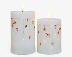 To hvide bloklys med glat overflade, hver med et flammefrit LED-lys i toppen. Lysene er dekoreret med små, festlige julemotiver og ornamenter, såsom slikstokke, hjerter, kringler, kristtorn, gyngeheste og gaveæsker, der hænger fra tynde guldfarvede snore rundt om den øverste del af lysene. Små indbyggede LED-lys er spredt over overfladen og giver en varm, glødende effekt.