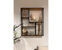 Vægmonteret reol med sort metalramme og træhylder, designet i et moderne geometrisk mønster med flere rum. Hylderne er dekoreret med forskellige pyntegenstande, herunder et indrammet botanisk billede, en glascylinder med tændt lys, en duftpind-diffuser, en lille træskulptur, vinglas, drikkeglas, en kunstig blomsterdekoration i en lille vase og en stak bordskånere. Udtrykket er moderne og stilfuldt, velegnet til stue eller entré.