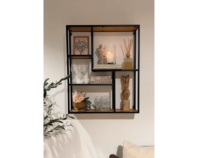 Vægmonteret reol med sort metalramme og træhylder, designet i et moderne geometrisk mønster med flere rum. Hylderne er dekoreret med forskellige pyntegenstande, herunder et indrammet botanisk billede, en glascylinder med tændt lys, en duftpind-diffuser, en lille træskulptur, vinglas, drikkeglas, en kunstig blomsterdekoration i en lille vase og en stak bordskånere. Udtrykket er moderne og stilfuldt, velegnet til stue eller entré.
