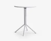 Rundt bord med en glat, hvid bordplade og en central metalfod. Foden deler sig i fire skråtstillede ben for stabilitet, og hvert ben har beskyttende endestykker. Designet er minimalistisk og moderne, velegnet til små rum eller uformelle omgivelser.