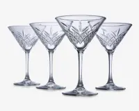 Sæt med fire klare glas med stilk, hver med en bred, konisk skål og indviklede geometriske mønstre skåret i den nederste del af skålen. Glassene har en solid fod og elegante, lange stilke, hvilket giver dem et sofistikeret og klassisk udseende.