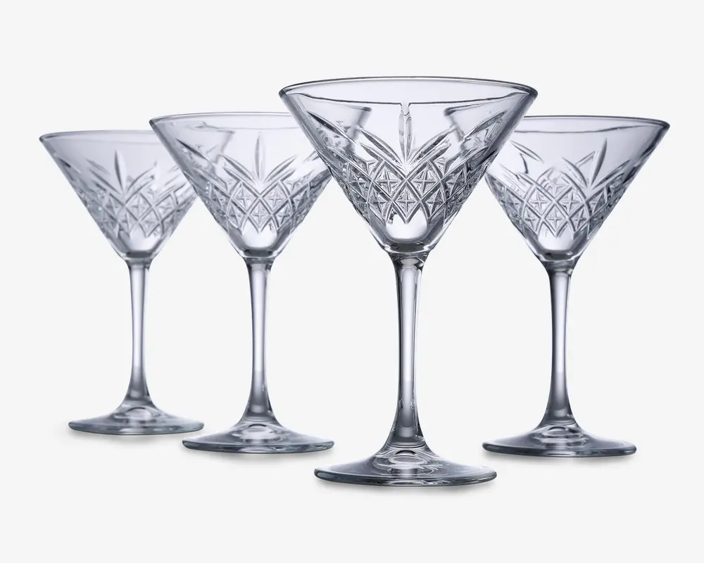 Sæt med fire klare glas med stilk, hver med en bred, konisk skål og indviklede geometriske mønstre skåret i den nederste del af skålen. Glassene har en solid fod og elegante, lange stilke, hvilket giver dem et sofistikeret og klassisk udseende.