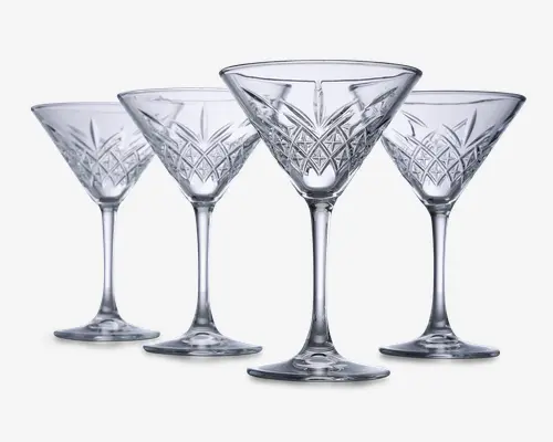 Sæt med fire klare glas med stilk, hver med en bred, konisk skål og indviklede geometriske mønstre skåret i den nederste del af skålen. Glassene har en solid fod og elegante, lange stilke, hvilket giver dem et sofistikeret og klassisk udseende.