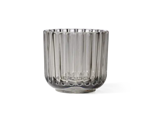 Klar glasbeholder med cylindrisk form og lodret rillet struktur langs siderne. Glasset har en tyk, solid bund og en bred åbning foroven. Det rillede design giver et dekorativt og taktilt udtryk, hvilket gør det velegnet til både funktionel og dekorativ brug.