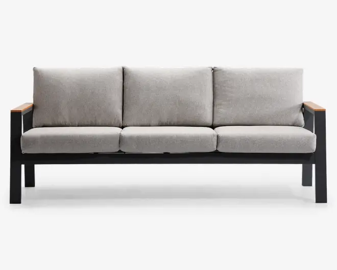 Moderne tresæders med tykke, lysegrå hynder på både sæde og ryg. Stellet er lavet af solidt sort metal med rene linjer, og armlænene har trædetaljer på toppen, som giver et varmt udtryk. Hynderne ser ud til at kunne tages af for nem rengøring.