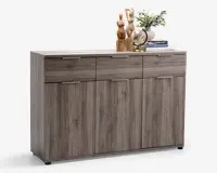 Et rektangulært skab med lysegrå træstruktur, der har tre øverste skuffer med slanke metalhåndtag og tre nederste låger med tilsvarende håndtag. Skabet har en glat, flad top, som er dekoreret med træfigurer af dyr, en lille globus, en vase med grønne grene og en stak bøger. Designet er moderne og minimalistisk med rene linjer og naturlig trætekstur.
