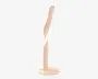 En moderne, minimalistisk lampe med et snoet, skulpturelt design. Lampen har en glat, mat overflade i en blød beige farve. Den står lodret på en rund, flad fod, og lampens krop snor sig elegant opad, hvilket giver et dynamisk og stilfuldt udtryk. Lyskilden ser ud til at være integreret langs lampens indvendige kurve og giver indirekte belysning.