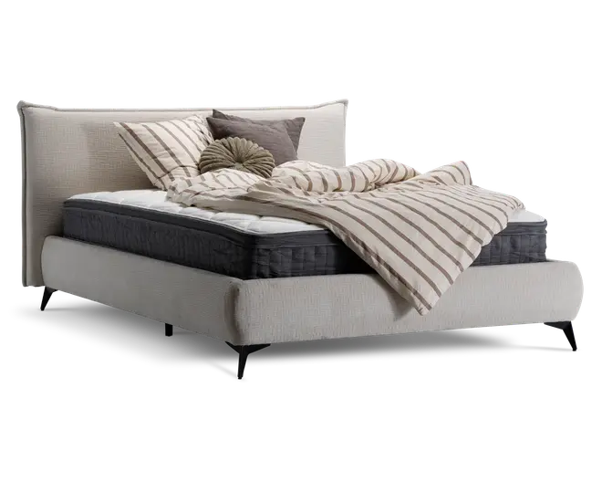 Moderne polstret sengegavl i lysebeige stof med høj, blød hovedgavl. Sengen har en tyk, mørkegrå madras og hvid topmadras. Sengetøjet består af en creme- og taupe-stribet dyne, matchende pudebetræk samt dekorative pyntepuder i neutrale farver og en rund, plisseret pude. Sengen står på slanke, skråtstillede sorte ben.