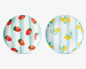 To runde tallerkener med farverige frugtmotiver. Den venstre tallerken har et mønster af røde jordbær med grønne blade på en hvid baggrund med lodrette grønne akvarelstriber. Den højre tallerken viser gule citroner med grønne blade på en hvid baggrund med lodrette blå akvarelstriber. Begge tallerkener har en blank overflade og et legende, sommerligt udtryk.