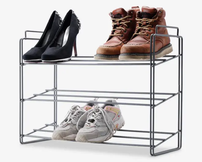 Et to-etagers skostativ i metal med et minimalistisk, åbent design. Stativet er sølvfarvet og har to hylder, som hver kan rumme flere par sko. På øverste hylde står et par sorte højhælede sko og et par brune læderstøvler, mens nederste hylde har et par lysegrå sportssko. Stativet har sidehåndtag for nem transport og en solid, stabil konstruktion.