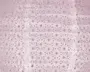 Lyserødt stof med et mønster af jævnt fordelte cirkulære prikker og små halvcirkelformede figurer. Materialet virker let krøllet og har en semi-transparent kvalitet, så noget lys kan trænge igennem. Designet giver et fint og luftigt udtryk, velegnet til dekoration eller mode.