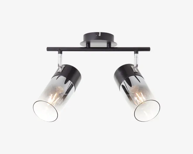 Moderne loftmonteret lampe med to justerbare cylindriske spotlys. Hvert spotlys har en sort metalbase og en klar glasafskærmning, så pærerne er synlige. Lampen er monteret på en vandret stang, der er forbundet til en rund loftsroset, alt sammen i en elegant sort finish.