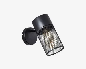 Væghængt lampe med cylindrisk sort metalskærm og netdesign. Nettet gør pæren synlig, som er en eksponeret filamentpære, hvilket giver et industrielt og moderne udtryk. Lampen er monteret på en rund sort base og har en justerbar arm, så lyset kan rettes.