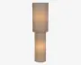 Høj minimalistisk lampe med to stablede cylindriske skærme i beige stof, der lyser blødt med varmt lys.