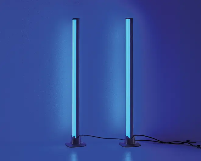 Et par høje, slanke, lodrette LED-lysstænger, der udsender et kraftigt blåt skær. Hver lysstang er monteret på en rund, flad fod og tilsluttet en strømkabel. Designet er minimalistisk og moderne, velegnet som stemnings- eller accentbelysning i nutidige indretninger.