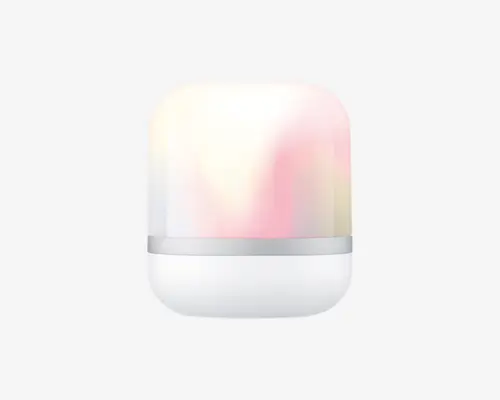 En kompakt, cylindrisk enhed med en glat, mat hvid bund og en gennemsigtig øverste del, der udsender et blødt, flerfarvet skær. Den øverste del skifter mellem pastelfarver som pink, gul og hvid, hvilket skaber en beroligende stemningsbelysning. En tynd sølvfarvet ring adskiller bunden fra den oplyste top og giver et moderne og minimalistisk udtryk.