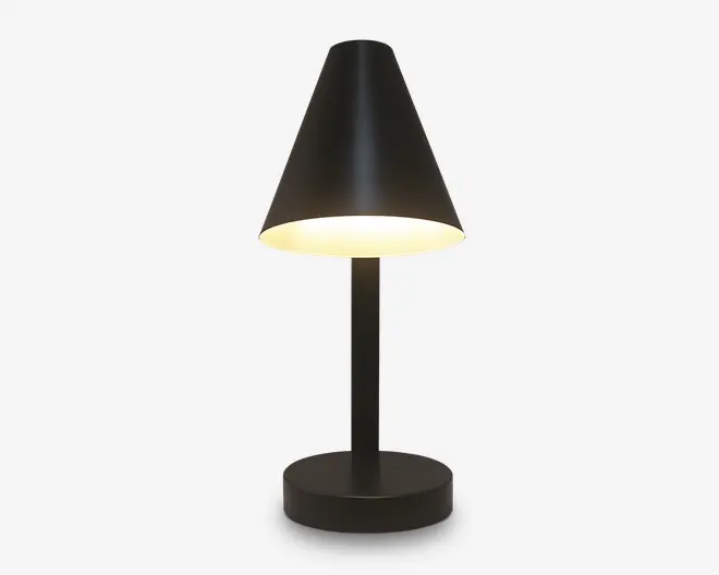 En moderne bordlampe med mat sort finish, der har en konisk lampeskærm, som leder lyset nedad. Lampen har en cylindrisk fod og en lige, slank stang, hvilket giver et minimalistisk og nutidigt udtryk. Lyset er varmt og diffust, hvilket egner sig til at skabe en hyggelig stemning.