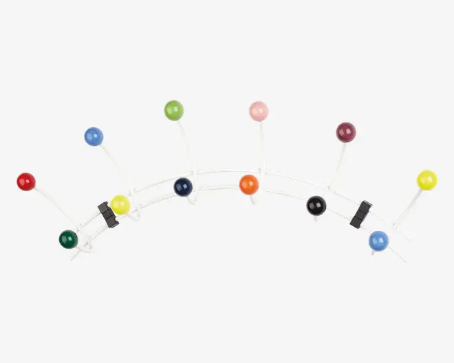 En vægmonteret knagerække med en hvid metalramme, der har flere kroge med store, runde, blanke kugler i forskellige farver, herunder rød, grøn, blå, gul, orange, lyserød, lilla og sort. Krogene er arrangeret i et legende, buet mønster, hvilket giver knagerækken et moderne og finurligt udtryk.