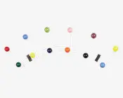 En vægmonteret knagerække med en hvid metalramme, der har flere kroge med store, runde, blanke kugler i forskellige farver, herunder rød, grøn, blå, gul, orange, lyserød, lilla og sort. Krogene er arrangeret i et legende, buet mønster, hvilket giver knagerækken et moderne og finurligt udtryk.