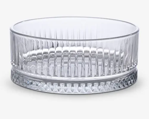 Klar glasskål med cylindrisk form, der har lodrette rillede linjer langs siderne for et tekstureret udseende. Bunden er tyk og solid, dekoreret med et diamantmønster for ekstra greb og visuel effekt. Kanten er glat og afrundet.