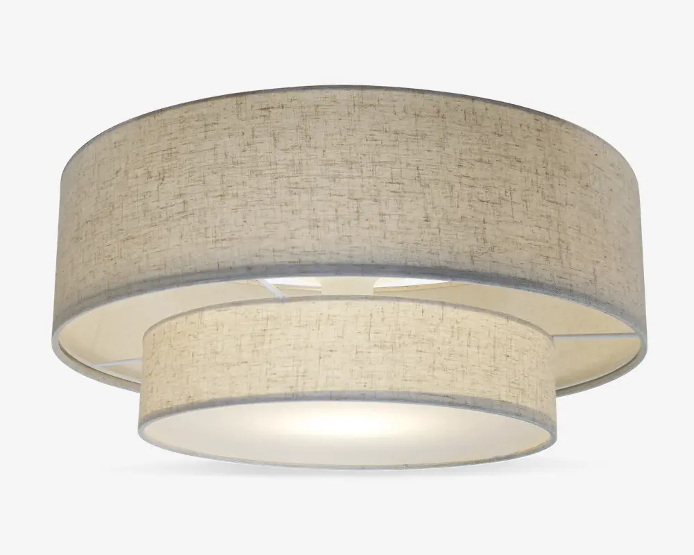 Et moderne loftarmatur med dobbelt tromledesign bestående af to koncentriske stofskærme i en neutral beige farve. Den ydre skærm er større og omgiver en mindre indre skærm, begge med et diskret tekstureret mønster. Bunden er dækket af en mat diffuser, der giver et blødt og jævnt lys. Armaturet har et rent, moderne udtryk, der passer til mange forskellige indretninger.