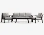 Moderne udendørs loungesæt bestående af en tre-personers sofa, to loungestole og et rektangulært sofabord. Møblerne har en robust, mørk metalramme med skrå ben og lysegrå, tykke sæde- og ryghynder for ekstra komfort. Armlænene er dekoreret med detaljer i naturtræ, hvilket giver et varmt præg til det moderne design.