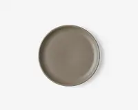 Rund tallerken med en glat, mat overflade i taupe farve. Tallerkenen har en let forhøjet kant og et minimalistisk, moderne design uden mønstre eller dekorationer.