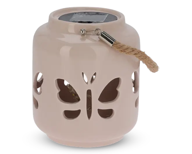 En rund, lysebeige lanterne af keramik med udskårne sommerfugle på siderne. Den har et kraftigt rebhåndtag, der er fastgjort med en metalbeslag, og et solpanel på toppen til opladning. Lanternen har en glat, blank overflade og er velegnet til udendørs eller dekorativ brug.