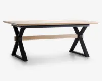 Rektangulært bord med en lys træbordplade og sorte metalben i X-form. Bordet har en tværgående støttebjælke i matchende lyst træ mellem benene for ekstra stabilitet. Designet kombinerer moderne og industrielle elementer med rene linjer og solid konstruktion.