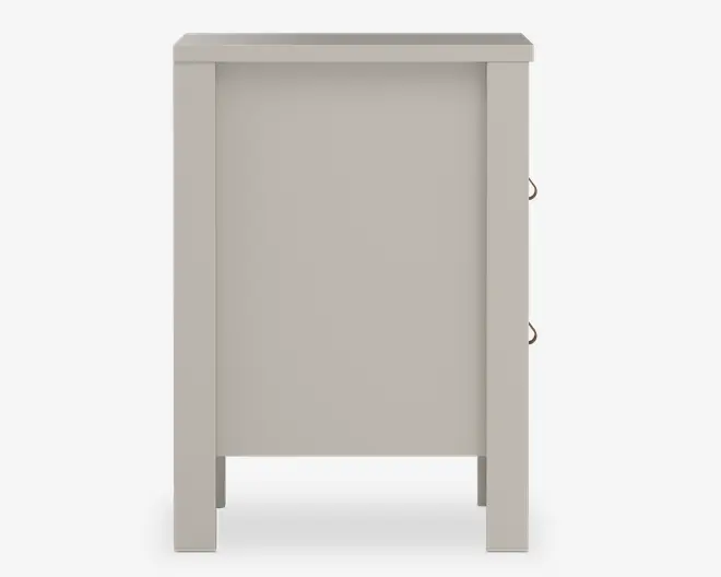 Sidevisning af et møbel med en glat, lys beige overflade. Designet har rene, lige linjer og et solidt panel indrammet af to robuste ben. Hængslerne på højre side indikerer, at der er en låge på modsatte side. Bunden er åben, hvilket giver frihøjde fra gulvet.