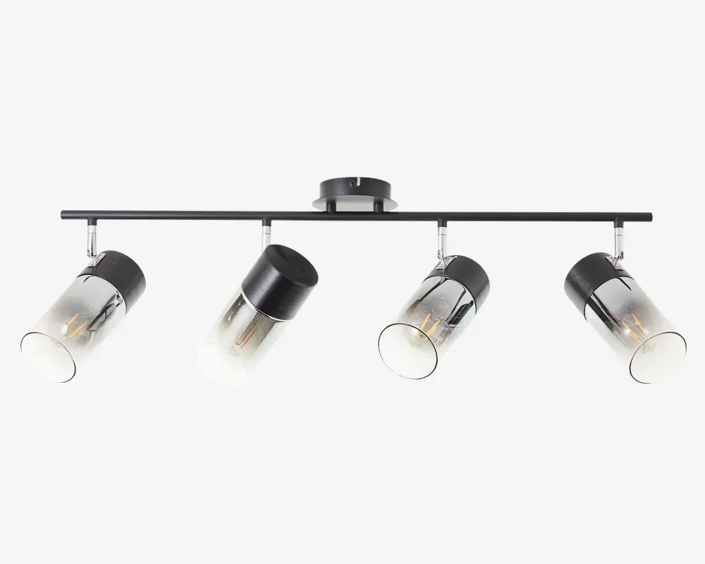 Moderne loftlampe med fire justerbare cylindriske spotlys. Hvert spotlys har en sort metalbase og en klar glasafskærmning, så pæren er synlig. Lampen er monteret på en slank, horisontal metalstang med en rund loftsroset i midten. Designet er minimalistisk og moderne, velegnet til forskellige indretninger.
