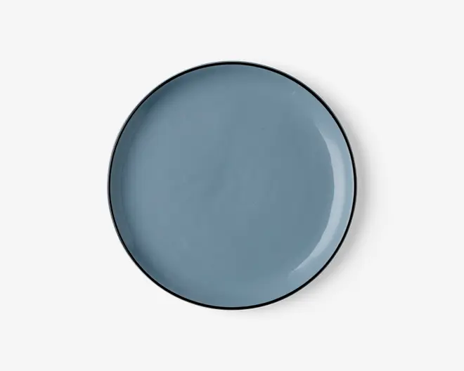 Rund tallerken med en glat, blank overflade i en afdæmpet blå farve. Kanten er tynd og let hævet med en diskret mørkere kant. Overfladen er jævn og uden tekstur, hvilket giver et moderne og minimalistisk udtryk.