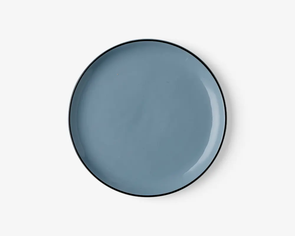 Rund tallerken med en glat, blank overflade i en afdæmpet blå farve. Kanten er tynd og let hævet med en diskret mørkere kant. Overfladen er jævn og uden tekstur, hvilket giver et moderne og minimalistisk udtryk.