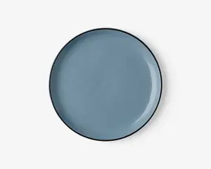 Rund tallerken med en glat, blank overflade i en afdæmpet blå farve. Kanten er tynd og let hævet med en diskret mørkere kant. Overfladen er jævn og uden tekstur, hvilket giver et moderne og minimalistisk udtryk.