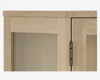 Nærbillede af et skabshjørne med lys egetræsfinish og en glat, mat overflade. Skabslågen har et rektangulært paneldesign og er monteret med et synligt metalhængsel i mørk finish. Træets årer er diskrete og løber både vandret og lodret, hvilket giver et moderne og rent udtryk.