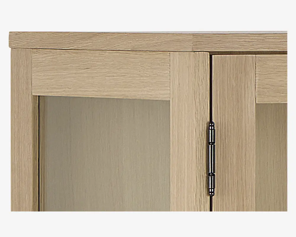 Nærbillede af et skabshjørne med lys egetræsfinish og en glat, mat overflade. Skabslågen har et rektangulært paneldesign og er monteret med et synligt metalhængsel i mørk finish. Træets årer er diskrete og løber både vandret og lodret, hvilket giver et moderne og rent udtryk.