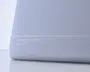 Nærbillede af en lysegrå pude med en glat, sømløs overflade og en diskret hvid linje, der løber vandret nær bunden. Puden har hvid tekst trykt med ordene "Air memory foam pillow" og "Breathe Zzz," hvilket indikerer, at den er lavet af air memory-skum for øget åndbarhed og komfort. Designet er minimalistisk og moderne.