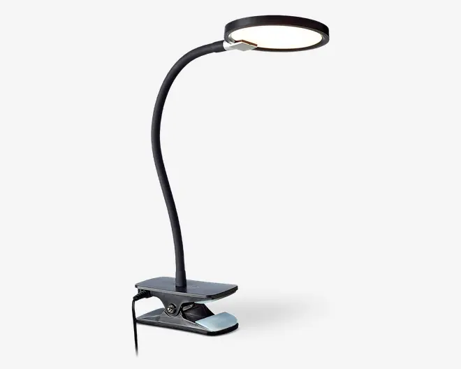 Fleksibel lampe med svanehals, rundt og fladt LED-lyshoved samt en robust klemmefod til fastgørelse på overflader. Lampen har et slankt, moderne design i sort med en let justerbar hals, så lyset kan rettes præcist. Klemmen har en polstret overflade for at beskytte mod skader og en synlig tænd/sluk-knap på siden.
