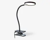 Fleksibel lampe med svanehals, rundt og fladt LED-lyshoved samt en robust klemmefod til fastgørelse på overflader. Lampen har et slankt, moderne design i sort med en let justerbar hals, så lyset kan rettes præcist. Klemmen har en polstret overflade for at beskytte mod skader og en synlig tænd/sluk-knap på siden.
