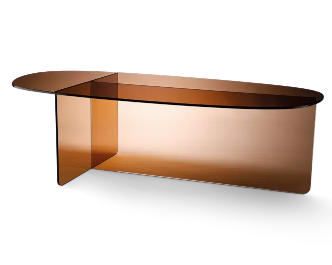 Elegant, moderne bord fremstillet udelukkende af tonet ravfarvet glas. Bordet har en glat, aflang oval bordplade med afrundede kanter og et unikt, krydsende understel, der både giver stabilitet og et markant visuelt udtryk. Glasset er halvgennemsigtigt, hvilket giver bordet et let og luftigt udseende, samtidig med at det bevarer en varm og sofistikeret tone.