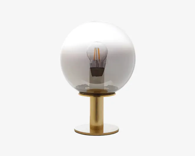 En moderne bordlampe med en klar glaskuppel, der fuldstændigt omslutter en synlig filamentpære. Lampen har en slank, cylindrisk fod med børstet guldfinish, hvilket giver et elegant og nutidigt udtryk. Designet fremhæver pæren som et centralt element og passer godt ind i minimalistiske eller moderne indretninger.