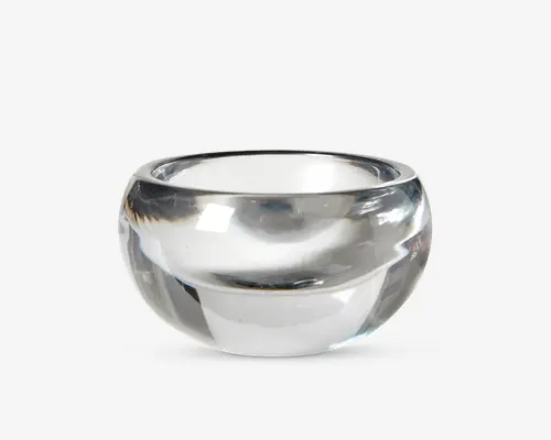En klar, rund glasskål med tykke vægge og en glat, poleret overflade. Skålen har en bred åbning og en dyb, afrundet bund, hvilket giver den et solidt og elegant udseende. Glassets gennemsigtighed gør det nemt at se indholdet.