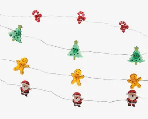 En festlig guirlande med fire forskellige typer farverige julemotiver: røde sløjfer, grønne juletræer med pynt, gule honningkagemænd med smilende ansigter og julemandsfigurer i røde dragter. Ornamenterne er jævnt fordelt på en tynd snor og skaber en glad og legende dekoration, der er velegnet til ophængning på vægge eller tværs over rum i juletiden.