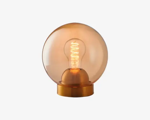 En kugleformet bordlampe med en varm, ravfarvet glasglobus, der omslutter en synlig glødepære. Lampen står på en metallisk guldfarvet base, hvilket giver et moderne og elegant udtryk. Den oplyste glødetråd tilføjer et vintagepræg, hvilket gør lampen velegnet til stemningsbelysning og dekoration.
