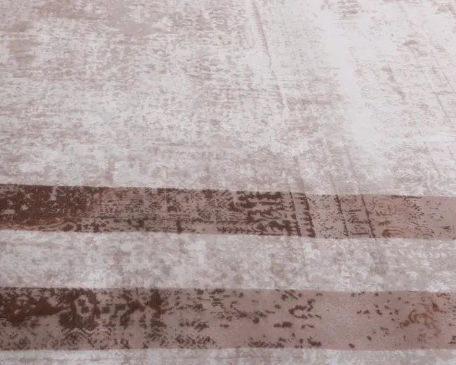 Overfladen har et blødt, tekstureret mønster i lyse beige og brune nuancer. Der er to brede, vandrette brune striber med et let slidt udseende, sat mod en meleret baggrund i creme og taupe. Materialet ser plysset og fløjlsagtigt ud, hvilket giver et indtryk af komfort og hygge.