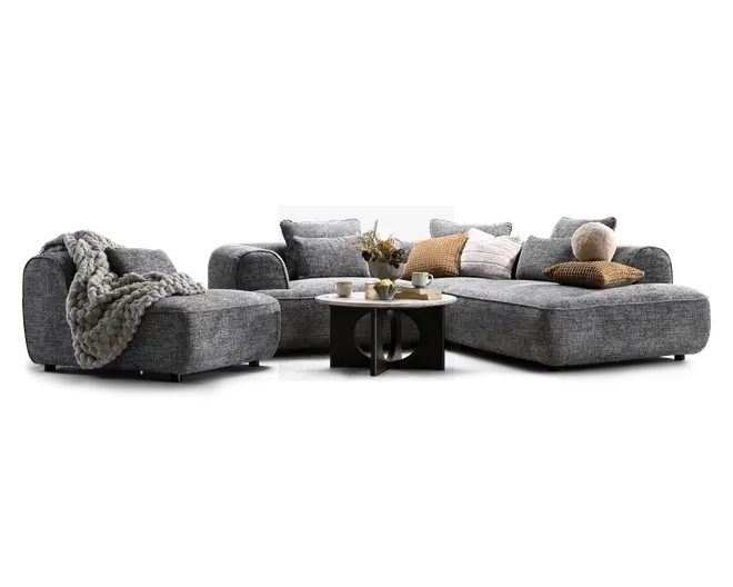 Grå modulsofa med en venstrevendt chaiselong og et langt sæde på højre side, stylet med flere pyntepuder, et kraftigt strikplaid og et lille rundt sofabord foran.