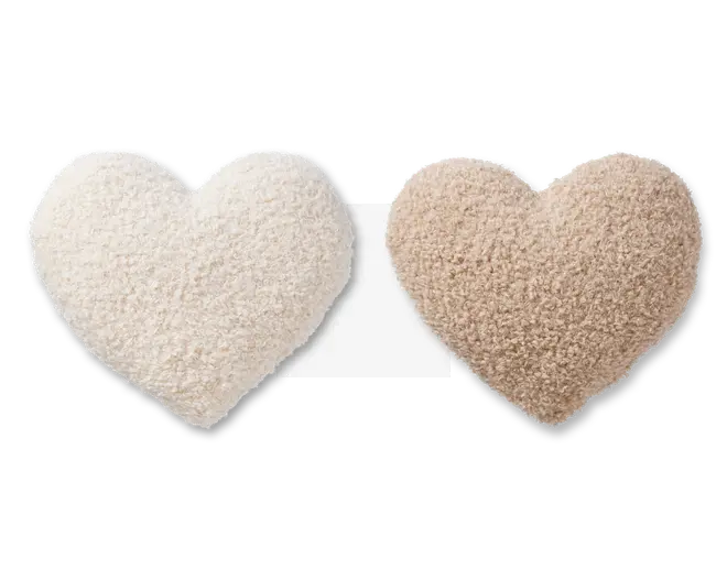 To hjerteformede puder vises, den ene i råhvid og den anden i lysebrun. Begge puder har en blød, fluffy og tekstureret overflade, der ligner sherpa- eller fleece-stof. Kanterne er afrundede, og det samlede udtryk er plysset og hyggeligt, velegnet til dekoration eller komfort.